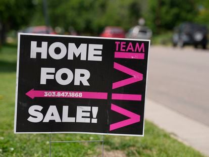 A for sale sign stands outside a single-family residence