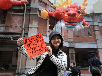 A woman holds a spring couplet with dragon patterns that she drew herself for the upcoming Lunar New Year celebrations at the Dihua street market in Taipei, Taiwan, Thursday, Feb. 8, 2024.