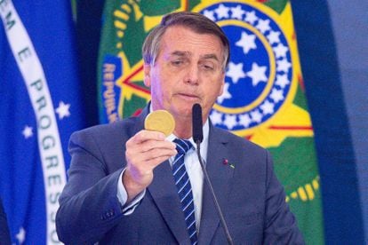Bolsonaro holds a gold coin while giving a speech in the Planalto Palace on May 3, 2021, in Brasilia.