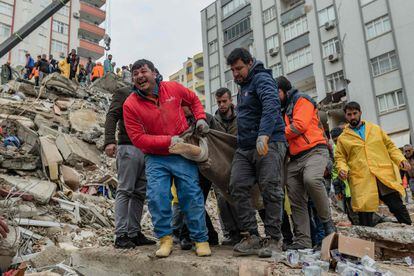 Rescuers carry a body found in the rubble in Adana on February 6, 2023, after a 7.8-magnitude earthquake struck the country's south-east. 
