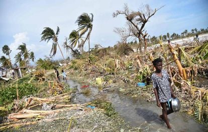 A girl walks amid the debris of crumbled buildings and damaged trees in the wake of Hurricane Matthew in Haiti.