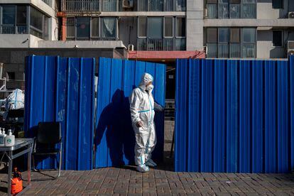 A worker with protective equipment in a neighborhood under confinement in Beijing on Monday.
