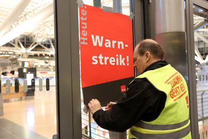 An airport security union representative posts a poster reading "Warning strike!" at Hamburg Airport, on March 22, 2023, in Hamburg, Germany.