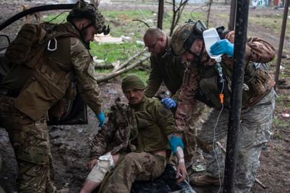 A Ukrainian soldier helps an injured colleague.
