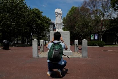 A man taking a picture of a headless Columbus statue in Boston. 