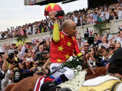 Jockey Mike Smith tips his helmet to the crowd as he rides Justify to the winner's circle after winning the 150th running of the Belmont Stakes horse race and Triple Crown on June 9, 2018, in Elmont,