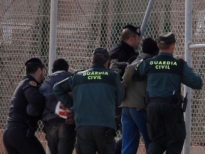 Civil Guard officers removing two migrants who had jumped the border fence in Melilla in 2014.