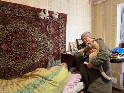 Liudmila, a 79-year-old retired nurse, bedridden in the apartment where she lives with Natacha, standing with her cat in her arms, in Lyman.