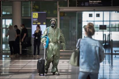 A passenger arrives from London in Barcelona’s El Prat airport on Friday wearing military coveralls and a gas mask.