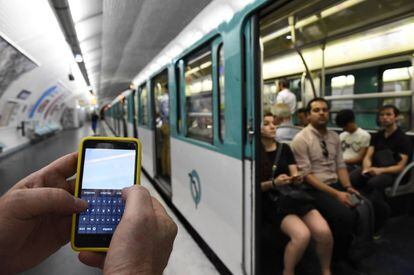 A man uses his phone in the Paris subway.