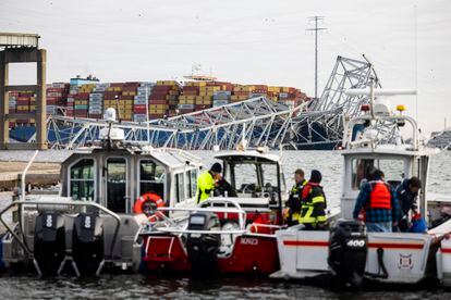 Emergency workers gather on the bank of the Patapsco River following the container ship accident (background), Tuesday in Baltimore. 