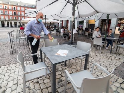 A waiter disinfects a table at a sidewalk café in Madrid.