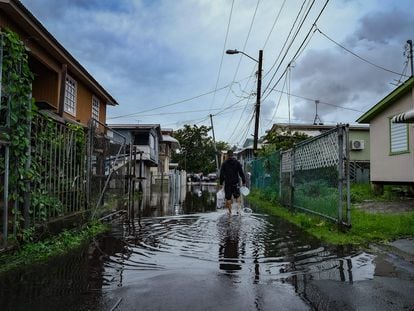 A man walks down a flooded street in Cataño, Puerto Rico, on September 19, 2022, after the passage of Hurricane Fiona.