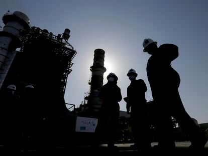 Saudi Aramco engineers walk in front of a gas turbine generator at Khurais oil field on June 28, 2021.