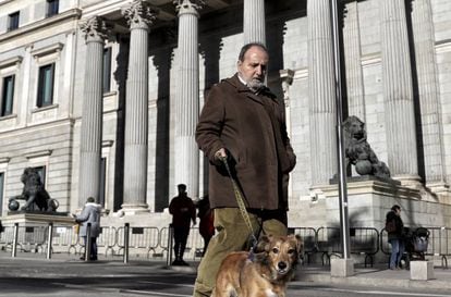 A man walks his dog in front of Spanish Congress.