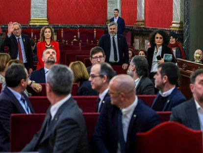 Catalan premier Quim Torra waves at the defendants inside the Supreme Court.