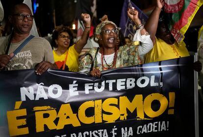 People hold a banner with a message that reads in Portuguese; "It isn't football, it is racism" during a protest in Rio de Janeiro, Brazil, on May 25, 2023.