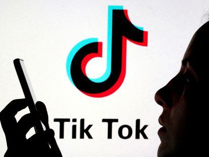 A person holds a smartphone as TikTok logo is displayed behind in this picture illustration taken November 7, 2019.