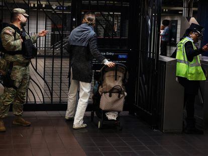 A member of the New York National Guard gestures to a subway rider at the 42nd Street station in the Times Square area of New York City, U.S., March 27, 2024.
