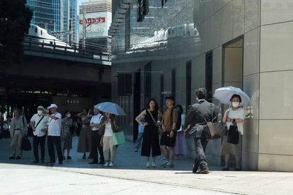 People wait in the shade for the green light on July 12 in Tokyo. 
