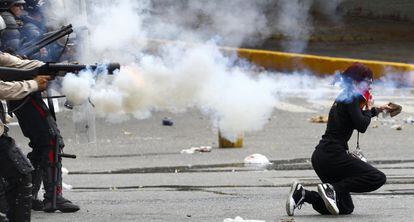 A protestor with a rock in hand is caught in a tear-gas battle with police in Caracas.
