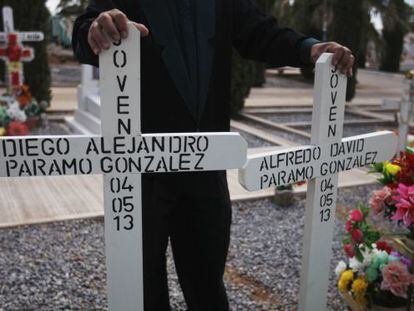 A funeral worker holds the crosses for the graves of two young men shot dead in Chihuahua on Saturday.