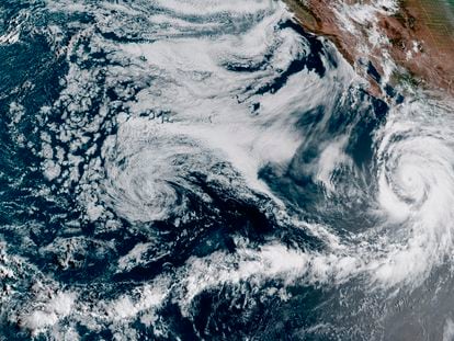 This Friday, August 18 EDT satellite image provided by the National Oceanic and Atmospheric Administration shows Hurricane Hilary, right, off Mexico’s Pacific coast.