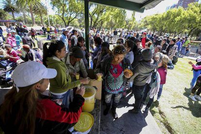 Cuban citizens on their way to the United States stranded in Quito stand in line for food and drink.