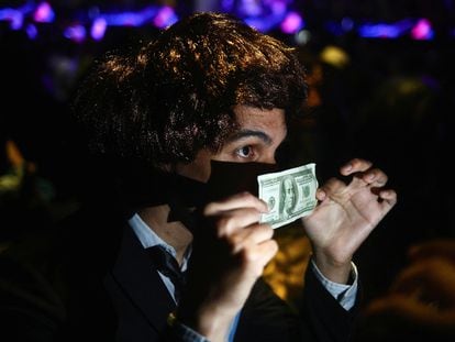 A Milei supporter holds up a $100 bill, at the candidate’s final rally before the first round of the presidential election, on October 18, 2023.