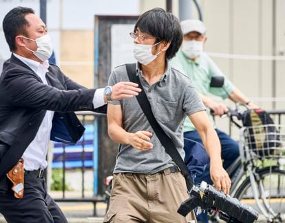 Tetsuya Yamagami, center, holding a weapon, is detained and accused of assassinating former Prime Minister Shinzo Abe.