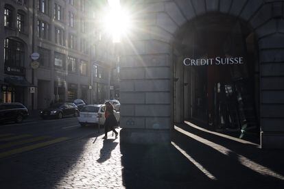 A woman walks past a Credit Suisse logo in Zurich on Monday, a day after it was taken over by UBS.
