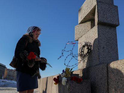 A woman places flowers in memory of Alexei Navalny at the monument to the victims of political repression in St. Petersburg, Russia.