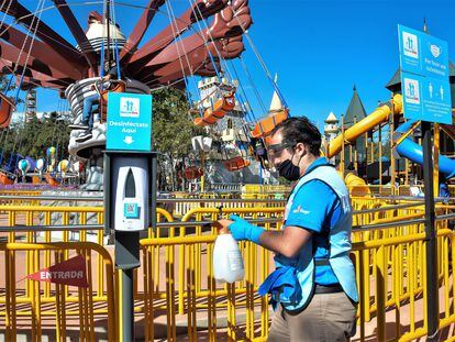A staff member disinfects the gates to an attraction during reopening day at Six Flags Mexico on October 23, 2020 in Mexico City, Mexico.