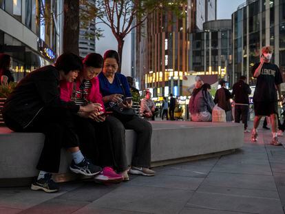 A group of women look at their phones in a central area of Beijing, China