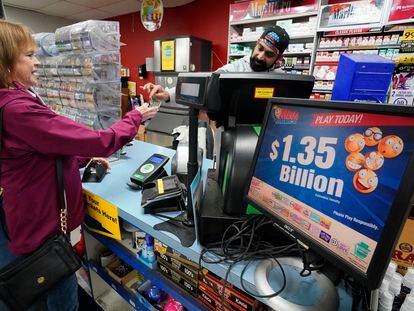 A Mega Millions sign displays the estimated jackpot of $1.35 billion as a customer purchases a Mega Millions ticket at the Cranberry Super Mini Mart in Cranberry, Pa., Thursday, Jan. 12, 2023.