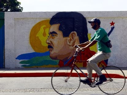 A man cycles past a mural of Venezuelan leader Nicolás Maduro.