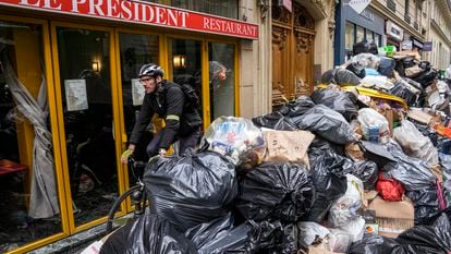 A cyclist rides past an uncollected garbage pile next to the cafe "The President" in Paris, on March 21, 2023.