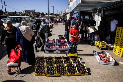Varias personas pasan junto a un puesto callejero de frutas y verduras cerca de la puerta de Damasco en Jerusalén, este viernes. 