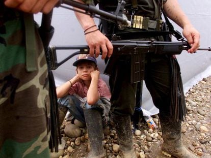 A boy sits among a group of FARC guerrillas in San Vicente del Caguán, in 2000.