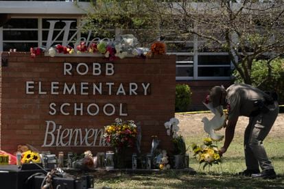 A police officer places flowers at the entrance to Robb Elementary School in Uvalde, Texas, on May 25, 2022.