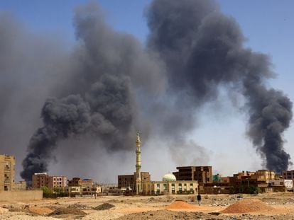 A man walks while smoke rises above buildings after aerial bombardment, during clashes between the paramilitary Rapid Support Forces and the army in Khartoum North, Sudan, May 1, 2023.