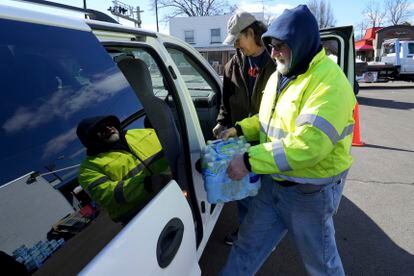 Volunteer Larry Culler helps load water into a car in East Palestine, Ohio, as cleanup from the Feb. 3 Norfolk Southern train derailment continues, Friday, Feb. 24, 2023.