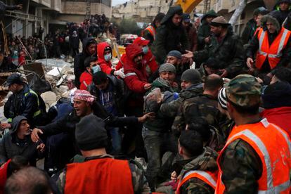 Civil defense workers and security forces carry an earthquake victim as they search through the wreckage of collapsed buildings in Hama, Syria.