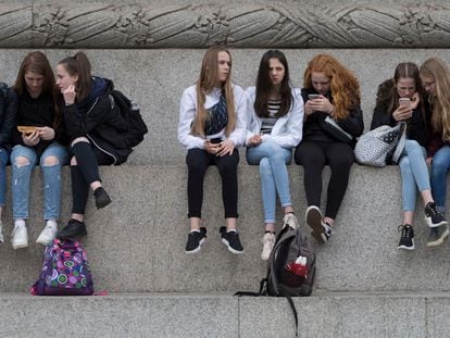 Teenagers use their phones in London, in May 2019.