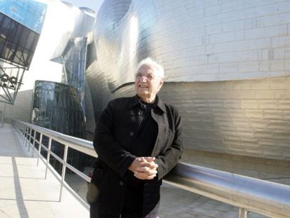 Frank Gehry standing in front of the Guggenheim Museum in Bilbao.