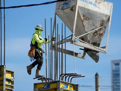 A worker guides a bin into position at a construction site, Tuesday, Jan. 24, 2023, in Miami.