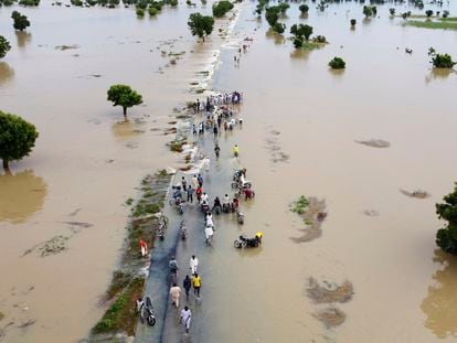 People walk through floodwaters after heavy rainfall in Hadeja, Nigeria, on September 19, 2022.