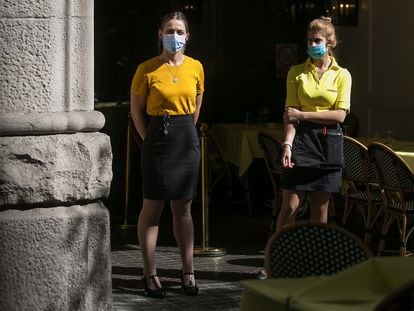 Two waiters at a sidewalk café in Catalonia, which has ordered the closure of all bars and restaurants from Friday.