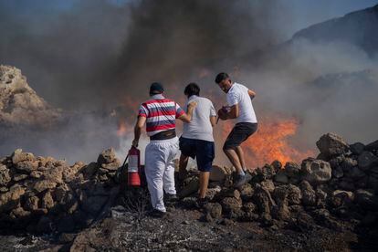 Local residents try to extinguish a fire, near the seaside resort of Lindos, on the Aegean Sea island of Rhodes, southeastern Greece, on July 24, 2023