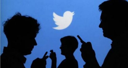 Smartphone users in front of a Twitter logo.